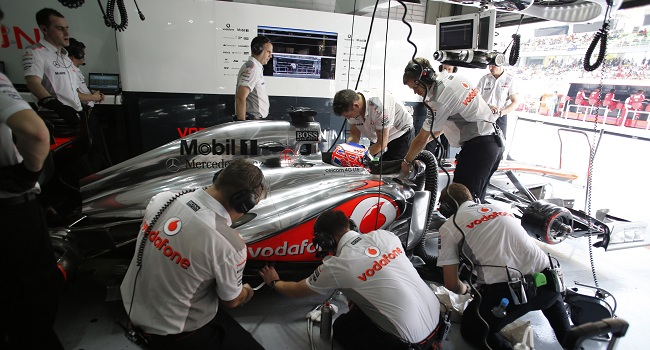 The team work on the MP4-28 of Jenson Button in the garage